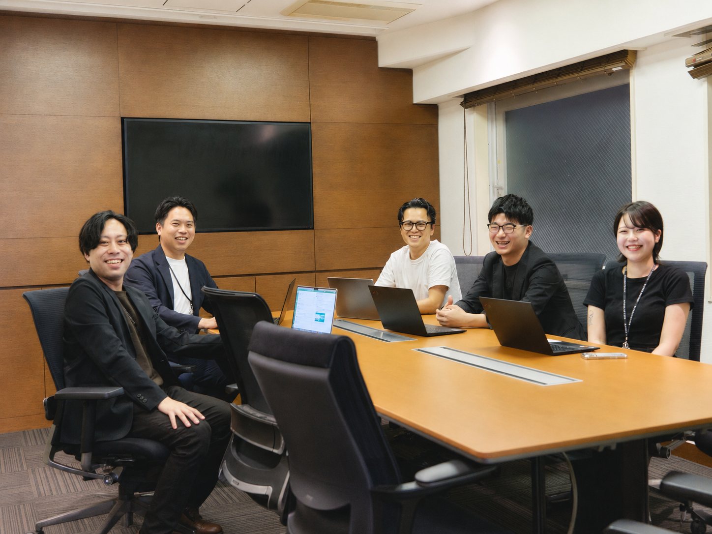 会議室で笑顔を見せるメンバー5名